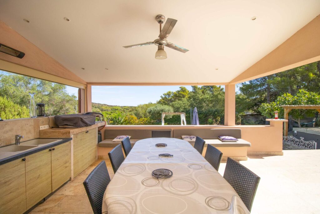 Terrasse couverte de la Villa La Chiappa avec grande table et cuisine d&rsquo;été